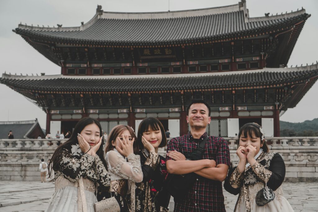 Visitors pose playfully at Gyeongbokgung Palace in Seoul, a famous Korean landmark.