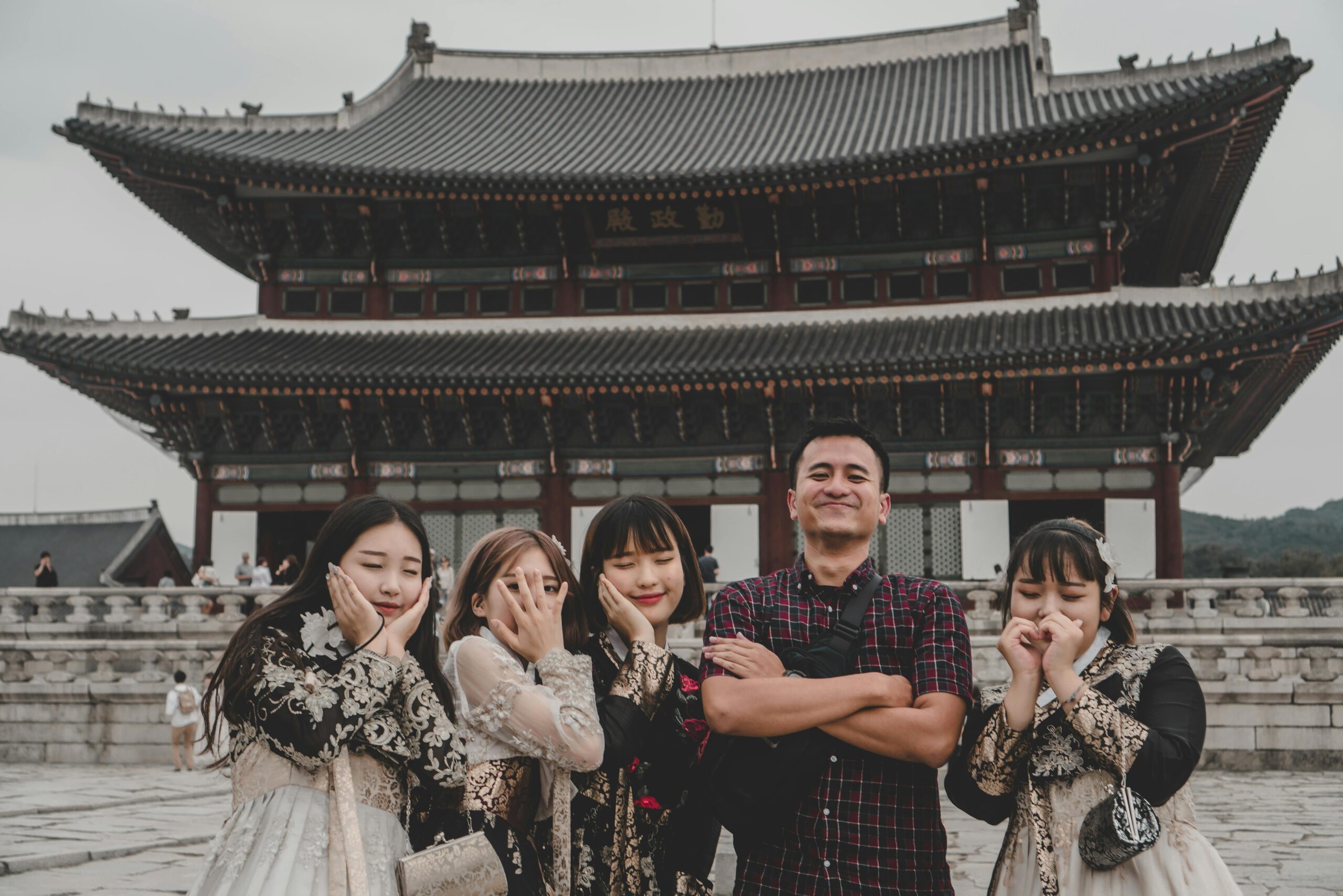 Visitors pose playfully at Gyeongbokgung Palace in Seoul, a famous Korean landmark.